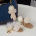Pompons ivoire, gant beige et bottillon en daim avec des crochets dorés près d’un sac en jean - Blanc Cassé
