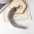 Dettaglio del ciondolo grigio in finta pelliccia, con anello dorato e terminale ornato di strass - Visone Polvere di Stelle