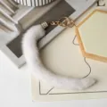 Vista dall’alto di un pendente bianco in pelliccia, con gancio dorato e chiusura metallica con strass - Bianco