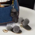 Pompons gris et breloques en bottine effet daim, avec mousquetons dorés sur un sac en jean - Gants / Gris