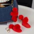 Détail de breloques rouges en forme de gant et de bottine, avec pompons doux et attaches dorées - Gants / Rouge