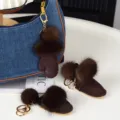 Gros plan sur des pompons en fourrure brun foncé et des bottines en daim avec anneaux dorés - Café