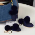 Breloques en peluche bleu marine, gant et botte, avec pompons et anneaux dorés près d'un sac en jean - Bleu foncé