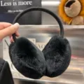 Close-up of plush black ear pads and a fabric-covered elastic band, held up by hand - Black