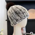 Close-up of mottled gray and brown striped fur-knit texture with a dark brown pompom - One Size (Elastic) / Frosted Brown