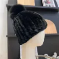 Close-up of a black ribbed knit hat with a fluffy pom-pom, shown on a mannequin head - One Size (Elastic) / Black