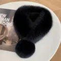 Black fluffy fur collar scarf with a round pom-pom, displayed flat on a white table - Black