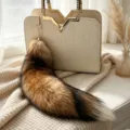 Brown and black gradient fox fur tail bag charm with a gold-tone clasp, shown beside a beige handbag - Red Fox Tail / 38 cm