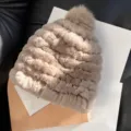 Close-up of the raised plush knit texture and matching pom-pom on a beige winter hat - One Size / Milk Coffee