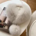 Ivory fluffy fur scarf collar with a rounded pom-pom detail, shown laid out on a chair - Milk Coffee