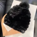 Close-up of a black plush knitted hat showing its raised texture and matching fluffy pom-pom - One Size / Black