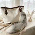 Gray-white fluffy fox-tail keychain with a gold-tone clasp, hanging from a cream tote bag - Gold Island Fox Tail / 38-40cm