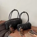 Borsa Boston nera trapuntata con zip, doppi manici e ciondolo a orsetto, mostrata in due misure - Nero