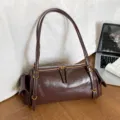 Brown cylindrical faux leather shoulder bag with long straps, gold hardware and side pockets - Glossy Brown