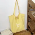 Bolso tote amarillo de nylon, con asas largas y letras blancas « byou merci », en posición vertical - 46*14*37 / Amarillo