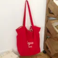 Bolso tote rojo de lona con asas largas y letras blancas, fotografiado frente a una pared clara - 46*14*37 / Rojo