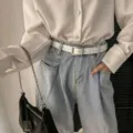 Weißer Damengürtel mit silberner Schnalle und Ösen, passend zu hellblauer Jeans im lässigen Look - Weiß