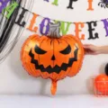 Close-up of an orange foil pumpkin balloon with a black jack-o'-lantern face and silver stem - Ghost Face Pumpkin Foil Balloon / 2 Pieces Set (73cm*61.5cm)