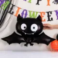 Close-up of a glossy black bat balloon with wide eyes and a fanged smile beneath Halloween letters - Bat Foil Balloon / 2 Pieces Set (72cm*60cm)