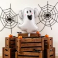 Halloween scene with a white ghost balloon, pink cheeks, black face, spiderwebs and pumpkins - Ghost Foil Balloon / 2pcs Pack (75cm*59cm)