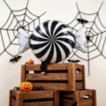 Black-and-white spiral foil balloon displayed among spiderwebs, toy spiders and pumpkin props - Candy Foil Balloon / 2pcs Pack (70cm*50cm)