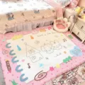 Bedroom view of a pink-bordered doodle rug with rabbits, a house, stars and “have a nice day” - 60x40cm / Pink Cartoon (FDDA097401)