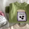 Detalle del tejido verde con cuello acanalado y aplique de tarro de mermelada con cuadros morados - XS / Verde