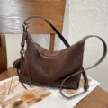 Brown suede bag with a curved silhouette, shoulder strap, zipper and metal hardware - Size: 30-10-20cm / Coffee
