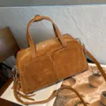 Close-up of a brown suede bag with leather trim, twin handles, zip top and two front pockets - 30x11x17cm / Brown