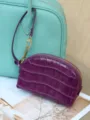 Purple crocodile-embossed pouch with a curved shape, gold zipper, and matching wrist strap - 15x5x10cm / Sea Anemone Purple