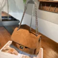 Detail view of a brown suede flap bag with diamond stitching and a silver chain shoulder strap - 30x11x20cm / Brown