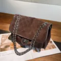 Close-up of a brown suede-textured flap, silver chain straps and clasp on an open magazine - 30x11x20cm / Coffee