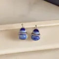 Close-up of blue-white glazed gourd earrings with silver-tone wire settings on a beige tray - Gourd Shape Style (HE37298) / Blue/Silver