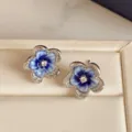 Close-up of blue and white glazed flower studs with crystal centers in a cream jewelry box - Gradient Flower Style (HE37299) / Blue/Silver