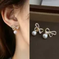Gold bow earrings with clear stones and dangling white pearls, worn and displayed on velvet. - Hollow Bow Pearl (6908)