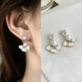 Close-up of blue and white enamel flower earrings with heart-shaped stones and pearl accents - White Blue Iris Style (4426)