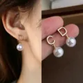Close-up of gold D and C letter earrings with dangling white faux pearls, worn and hand-held - Letter Pearl Tassel (4813)