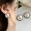 Close-up of pink tulip studs with green leaves, set on white discs with black and gold rims - Pink Tulip Round Style (4809)