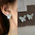 Close-up of blue-green enamel butterfly earrings with pearl centers, shown worn and as a pair - Zirconia Mambo Green Butterfly (4685) / Silver