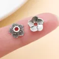 Gros plan de deux perles florales argentées sur un doigt, avec spirales et pétales texturés - Calotte Fleur Spirale (16314) / 10 Pièces/Paquet / Argent antique