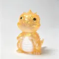 Close-up view of a translucent amber dinosaur figurine with gold glitter and pearl-white belly - Maltose Dinosaur / Orange