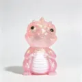 Pink glittery dragon figurine with a pearlescent finish, seated against a clean white background - Maltose Dinosaur / Pink