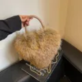 Close-up of a fluffy brown heart-shaped bag with a braided handle and gold chain strap - Khaki