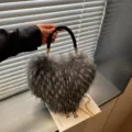 Gray faux-fur heart-shaped bag shown in hand, with a black woven handle and gold chain strap - Gray