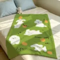 Green plush blanket laid on a bed, with white puppy illustrations, orange dots and printed words - Dark Green Cartoon Dog (FMTA177204) / 60x40cm
