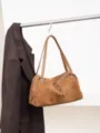 Tan suede bag hanging from a metal rail, featuring twin handles, tassel accents and a silver zipper - 35x12x23cm / Caramel color