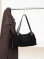 Black suede-texture handbag with twin handles hangs beside a brown striped coat against a white background - 35x12x23cm / Black