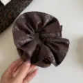 Primer plano de tela fruncida marrón oscuro con manchas claras de leopardo sobre fondo blanco - Coletero Cintura Fina Café