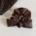 Vista plana de un coletero marrón oscuro fruncido con lazo de estampado leopardo sobre blanco - Coletero con Lazo Café / Café