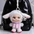 White long-eared plush doll in a pink striped vest, hanging on a black backpack with a soccer charm - Sheep Style (540081) / White